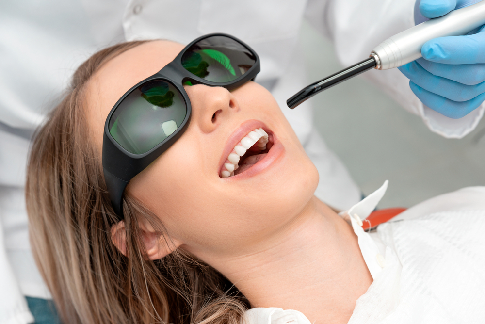A person undergoing dental treatment with protective eyewear, likely at Spencer Dental offering Laser Therapies