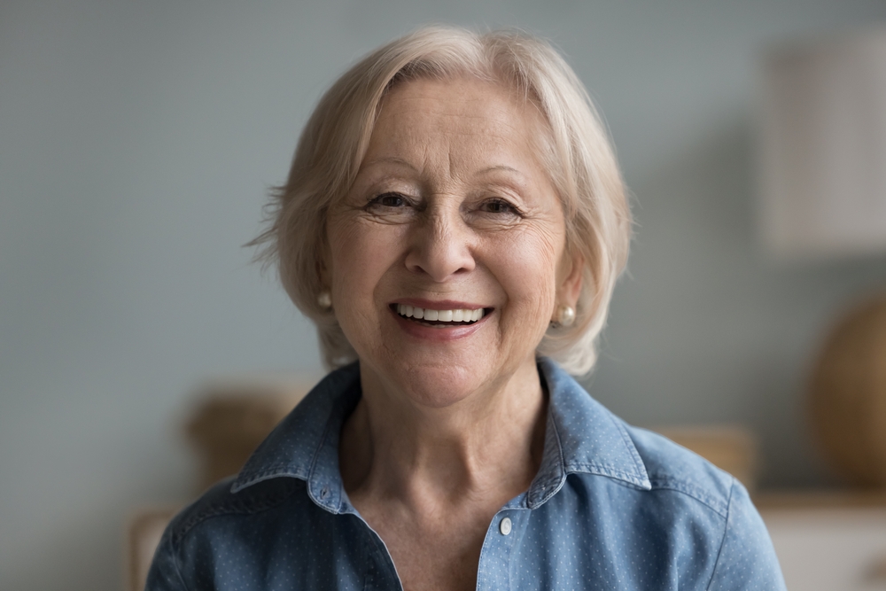A headshot of a happy, beautiful retired woman, advertising Dentures and Spencer Dental in Maryville